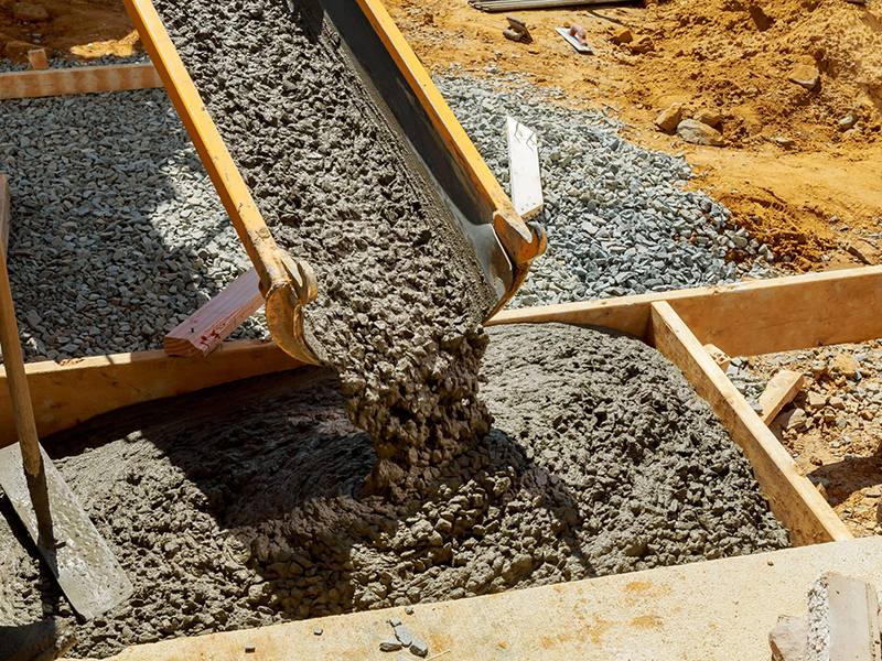 trabajador-construccion-vierte-cemento-acera-obras-hormigon-camion-mezclador-carretilla-1-scaled